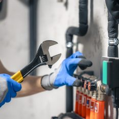 A man installs a heating system in a house and checks the pipes with a wrench. Adjusting heating valves in a residential building. A plumbing and heating technician works.
