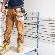 Professional in overalls with tools on the background of the repair site.